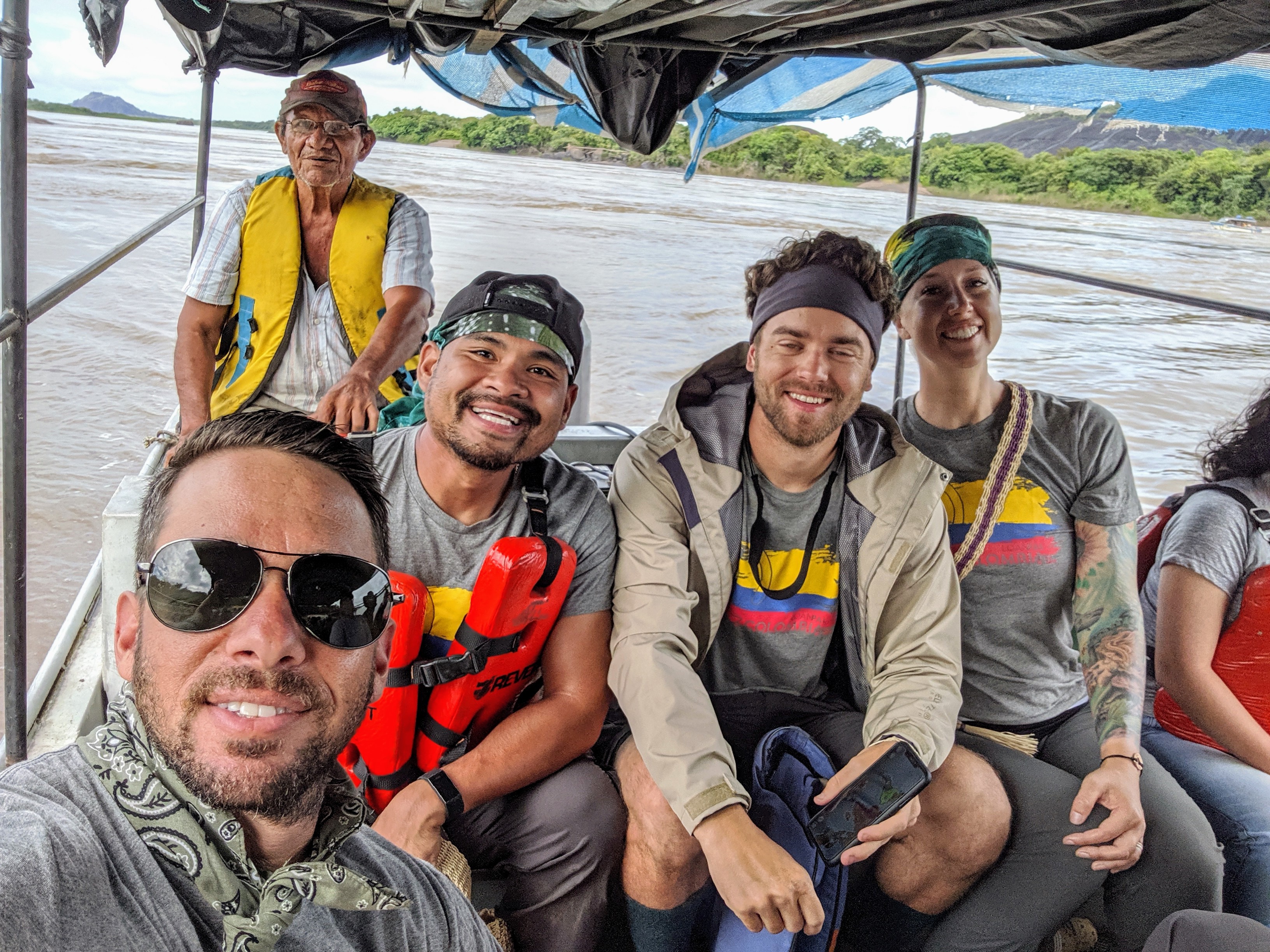 A group of people in a boat, smiling for a picture, on a remote jungle river in colombia,